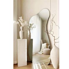 a large white vase sitting next to a tall mirror