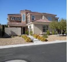 a large house that is in the middle of some bushes and trees on the side of the road