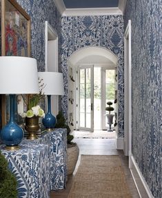 a hallway with blue and white wallpaper, two lamps on either side of the door