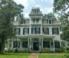 a large white house sitting on top of a lush green field