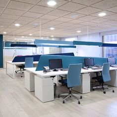 an empty office with blue and white desks in the middle of it's walls