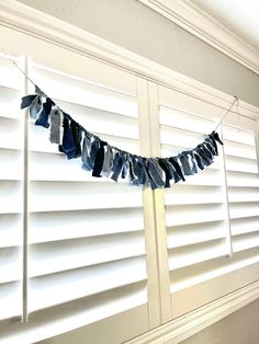 clothes hanging on a line in front of shutters with white paint and blue paper