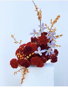 a white vase filled with red and white flowers