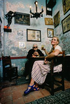 two people sitting at a table in a room with blue walls and pictures on the wall