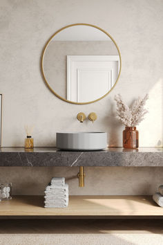 a bathroom with a round mirror above the sink and marble counter top, along with gold accents