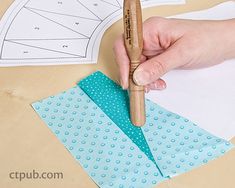 a person is cutting out some paper with a wooden ruler on top of the table