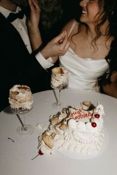 a bride and groom sitting at a table with a cake in the shape of a heart