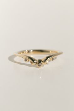 a gold ring with three small diamonds on it's side, sitting on a white surface