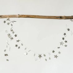 silver stars are hanging from a wooden branch