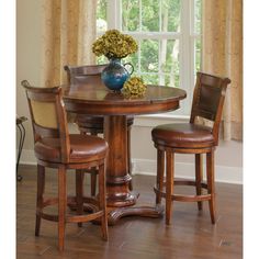 a dining room table with two chairs and a vase on top of it, in front of a window