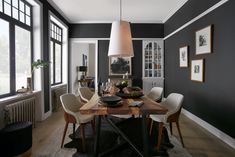 a dining room with black walls and white chairs