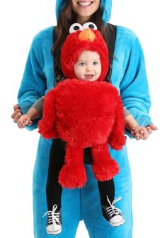 a woman holding a child in a sesame character costume