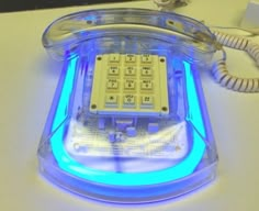 an old fashioned phone is glowing blue and has buttons on the front, side, and back