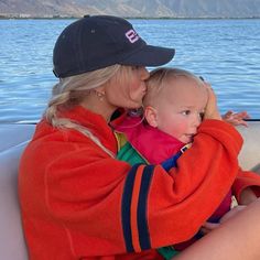 a woman holding a baby in her arms while sitting on the back of a boat