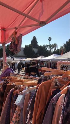 an outdoor market with lots of clothes on display