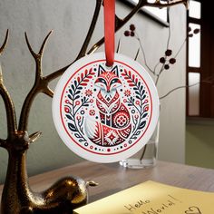 an ornament hanging from a tree on a table next to a note and pen