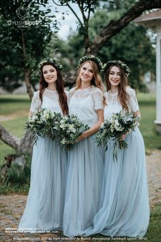 three bridesmaids in blue dresses with flowers on their head and bouquets around their necks