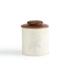 a white canister with a wooden lid and flower design on the front, sitting against a white background