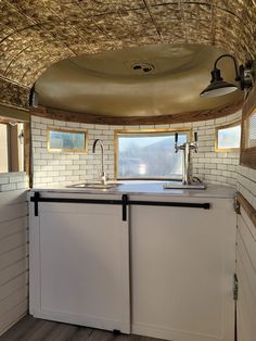 the inside of a tiny kitchen with white cabinets and wood flooring on the walls