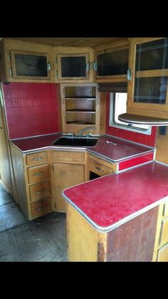 an old camper kitchen with red counter tops and wooden cabinetry is shown in this image