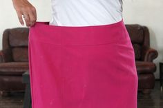 a woman wearing a pink skirt and white shirt is holding her hand in the pocket