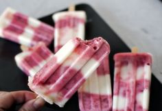 popsicles with red and white toppings are on a black plate, ready to be eaten