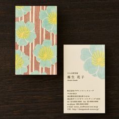 a business card with flowers on it sitting next to a piece of paper that has japanese writing