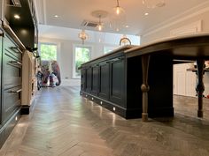 an empty kitchen with black cabinets and wood flooring on the walls, along with lights hanging from the ceiling