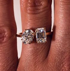 a woman's hand with an engagement ring and two diamond stones on the band