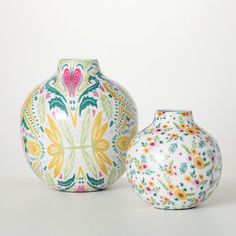 two colorful vases sitting next to each other on a white surface with floral designs