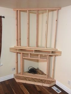 an unfinished room with wooden shelves and wires in the middle, on top of hard wood flooring