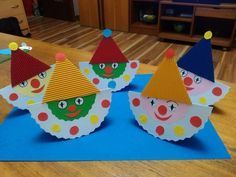 three paper clown hats sitting on top of a blue mat next to a wooden table