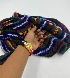 a person's hand holding onto a multicolored knitted blanket