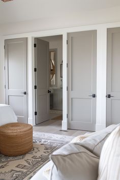 a living room filled with furniture and white doors in the middle of it's walls