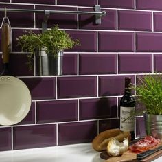 a kitchen with purple tiles and white counter tops, including a potted plant next to a bottle of wine