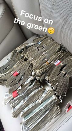 a pile of money sitting in the back seat of a car with text focus on the green