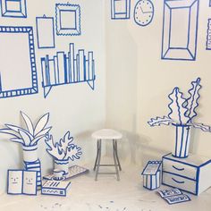 blue and white artwork on the wall in a room with bookshelves, planters, and other items