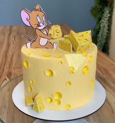 a cake decorated with yellow dots and a cartoon mouse on top is sitting on a table