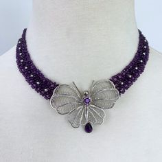 Amethyst woven necklace with vintage silver butterfly, beads & clasp. 1.5 mm amethyst beads interwoven with silver faceted beads. All Sterling Silver items are white gold plated to prevent oxidation. Intricately woven Amethyst beads arranged in a graduated pattern from inside to the outside diameter to follow the natural curve of the neck. Sterling Silver butterfly centerpiece carries a faceted amethyst stone (4 mm) and faceted teardrop-shaped amethyst suspended at the bottom. The necklace with Silver Beaded Necklaces With Faceted Amethyst, Silver Beaded Necklace With Faceted Amethyst Beads, Silver Amethyst Beaded Necklace With Faceted Beads, Handmade Elegant Amethyst Beaded Necklaces, Purple Amethyst Jewelry With Silver Beads, Elegant Amethyst Jewelry With Sterling Silver Clasp, Elegant Purple Jewelry With Silver Beads, Purple Beaded Jewelry For Formal Occasions, Luxury Handmade Purple Jewelry