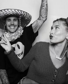 a man and woman with tattoos on their arms, wearing sombrero's