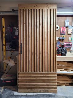 a large wooden door sitting inside of a garage next to a pile of wood planks