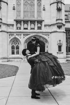 black and white photograph of a man kissing a woman in front of a large building