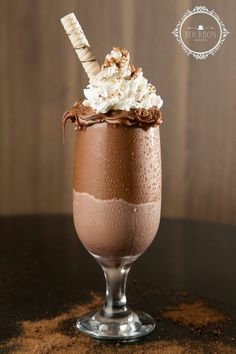 an ice cream sundae with chocolate and whipped cream in a glass on a table