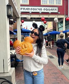 a woman in mickey ears is holding some bread