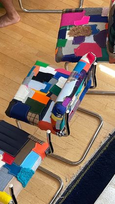 a colorful chair sitting on top of a hard wood floor next to a pile of folded fabric