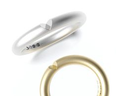 two gold and silver rings on a white surface with the word love written in it