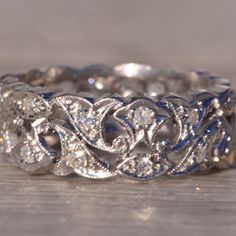 an intricately designed wedding ring with blue and white stones on the side, sitting on a wooden surface