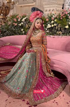 a woman sitting on top of a pink couch wearing a bridal gown and veil