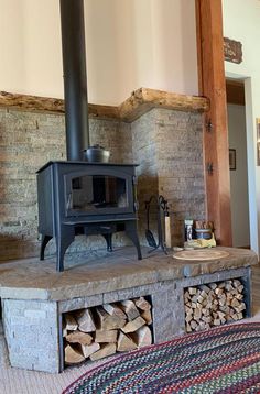 a wood burning stove sitting inside of a living room next to a pile of firewood