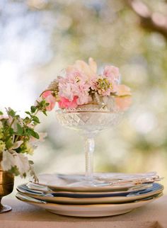 the table is set with plates, silverware and flowers in vases on it